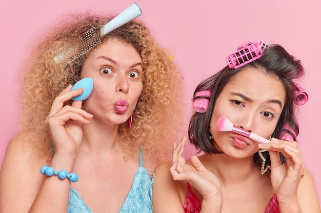 Binnenopname van multi-etnische jonge vrouwen die make-up doen met cosmetische borstel