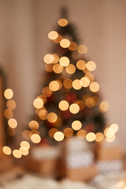 Binnenopname van wazig lichtviering op kerstboom, glanzende dennenboom met huidige dozen eronder, gelukkig nieuwjaar.