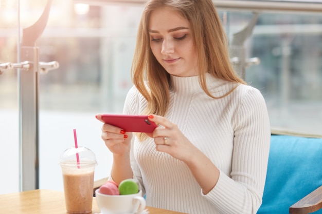 Binnenschot van jonge aanbiddelijke vrouwelijke zitting bij lijst in cafetaria