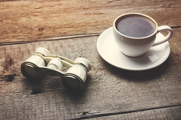 Бинокль и кофе на деревянном столе