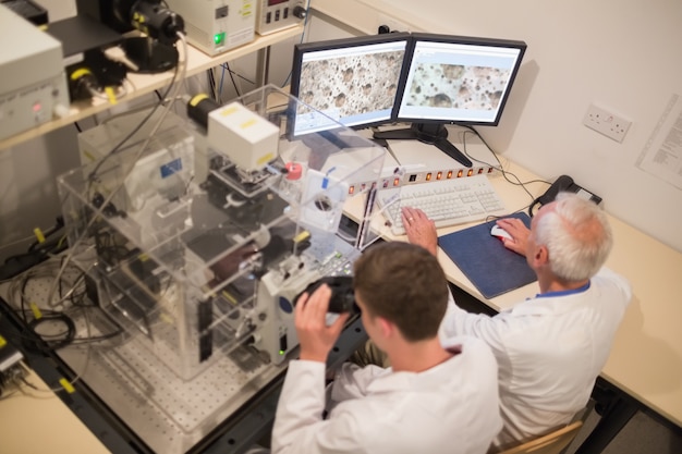 biochemist and student looking at microscopic images on computer