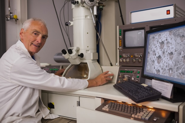 Biochemist using large microscope and computer