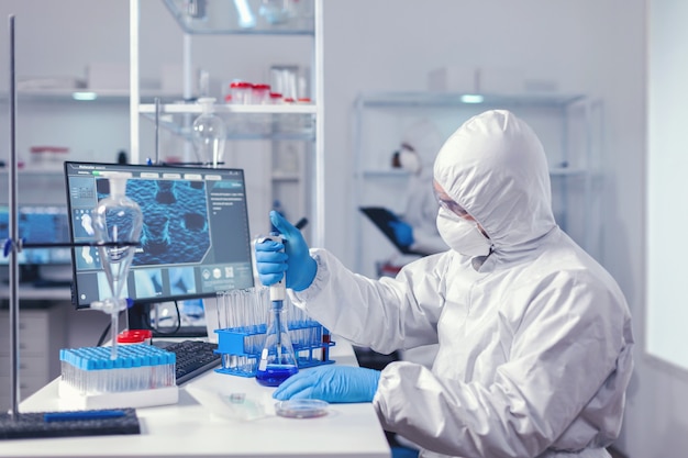 Biochemistry engineer conducing coronavirus experiment using automatic pipette. Chemist in modern laboratory doing research using dispenser during global epidemic with covid-19.