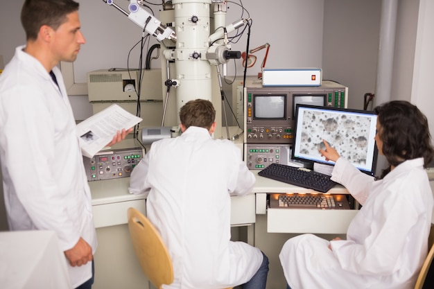 biochemistry students using large microscope and computer