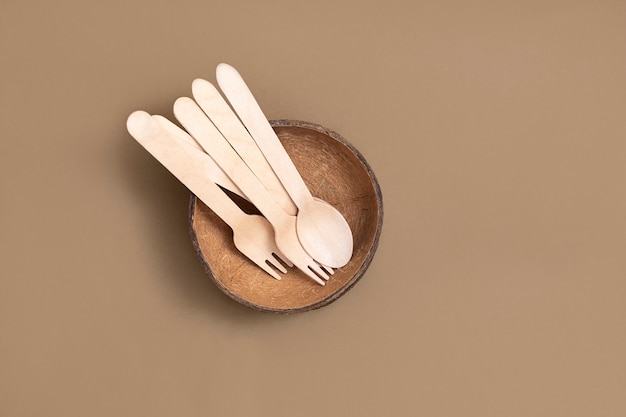 Biodegradable cutlery (spoon, forks, coconut bowl) on neutral brown