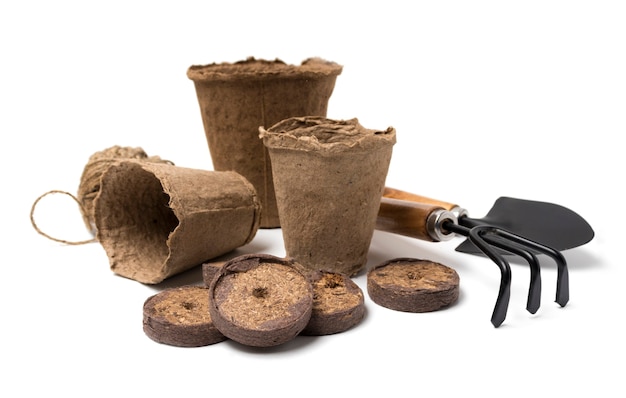 Biodegradable peat pots, peat tablets, garden tools and rope isolated on white background