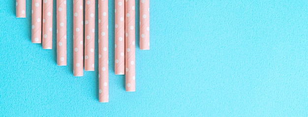 Biodegradable spotted pink paper straw set on blue table background design concept of environmental protection for Earth Day