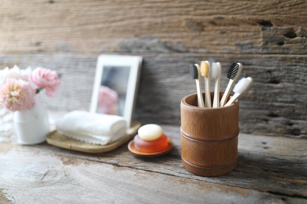 Biodegradable toiletries bamboo toothbrush and natural soap and mirror and roses vase