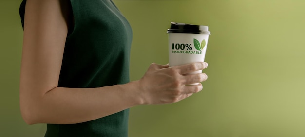 Biologisch afbreekbaar en composteerbaar verpakkingsconcept Close-up van vrouw met een warme kop koffie tegen een groene muur Geen afvalmateriaal Milieuzorg Hergebruik Hernieuwbaar voor een duurzame levensstijl