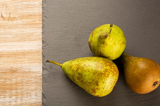 Biologisch geteelde peren op zwarte leisteen en oud hout