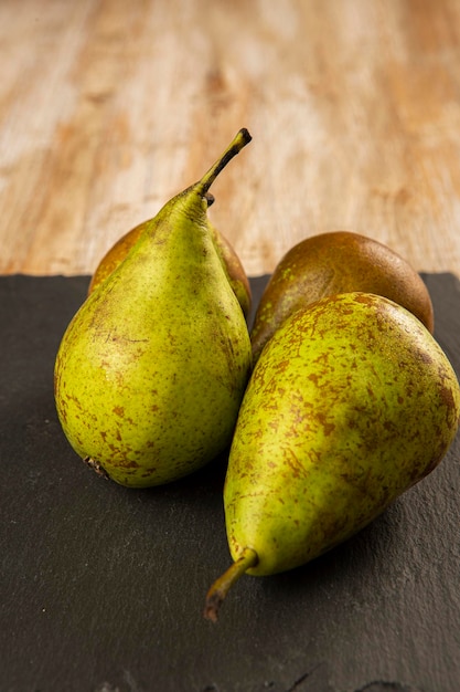 Biologisch geteelde peren op zwarte leisteen en oud hout