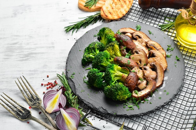 Biologisch voedsel Gebakken champignons en broccoli op een zwarte stenen plaat Rustieke stijl Bovenaanzicht