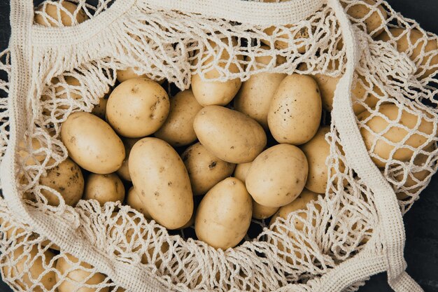 Biologische aardappelen Verse rauwe aardappelen in witte katoenen zak op donkere achtergrond bovenaanzicht