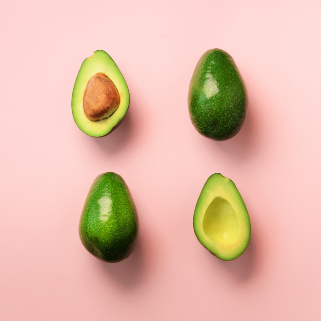 Biologische avocado met zaad, avocado helften en hele vruchten op roze achtergrond. Groen avocado patroon in minimale platte lay-stijl.