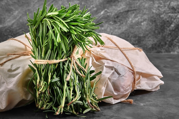 Biologische boeket verse rozemarijn op een grijze achtergrond. Een mooi gebonden bos vers gras. Levering van producten, kopieën van de ruimte.