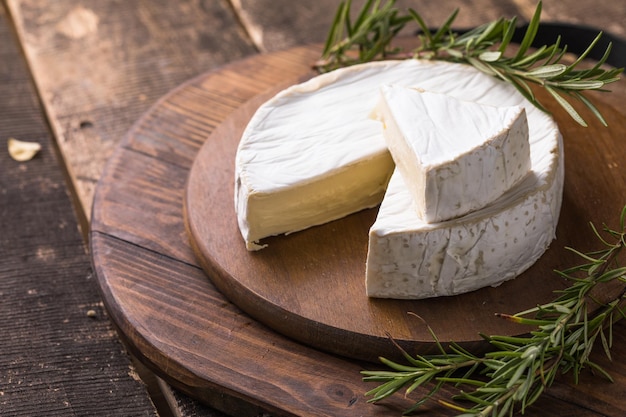 Biologische boerderij camembert of brie kaas op een houten bord met rozemarijn en noten, honing.