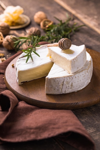 Biologische boerderij camembert of brie kaas op een houten bord met rozemarijn en noten, honing.