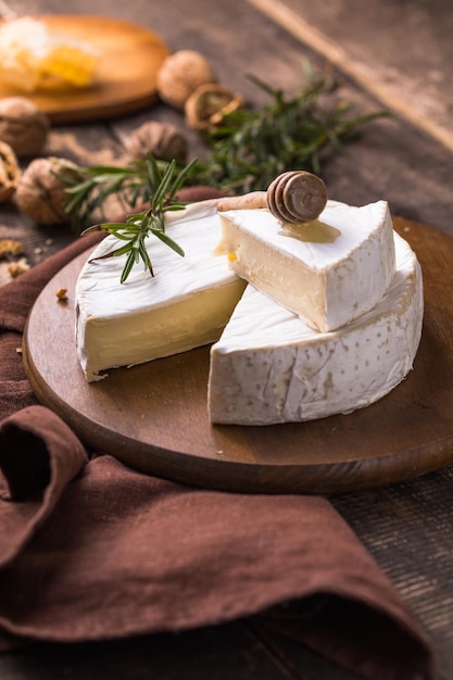 Biologische boerderij camembert of brie kaas op een houten bord met rozemarijn en noten, honing.