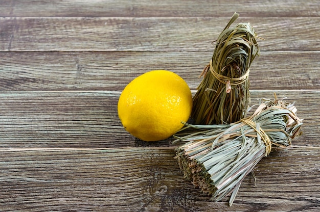 Biologische droog citroengras (cymbopogon flexuosus) in trossen en citroenfruit op een houten tafel. kruiden voor thee.