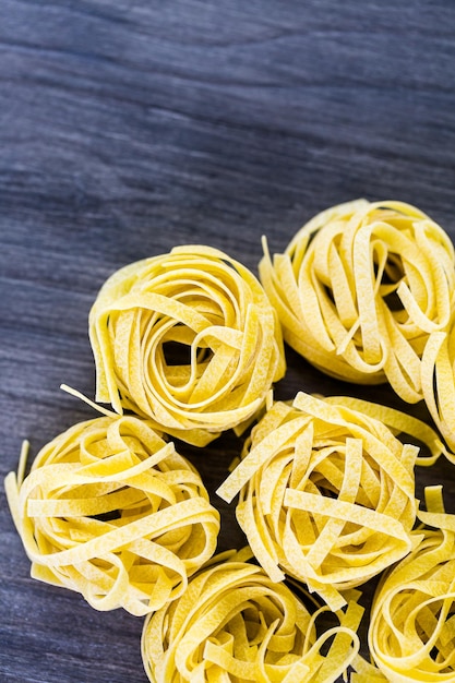 Biologische fettuccine nesten pasta op een houten bord.