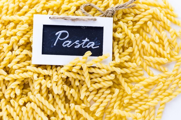 Biologische gele gemelli pasta op een witte achtergrond.