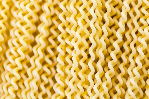 Biologische gele lange pasta spiralen op een witte achtergrond.