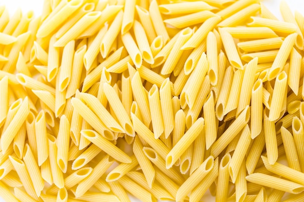 Biologische gele rigate pasta op een witte achtergrond.