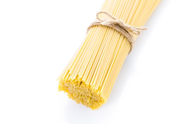 Biologische gele spaghetti pasta op een witte achtergrond.