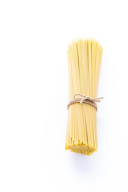 Biologische gele spaghetti pasta op een witte achtergrond.