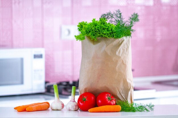 Foto biologische groenten in papieren zak op tafel voor het koken van groenteschotels en salades in de keuken. gezond eten, uitgebalanceerd dieet. schoon eten