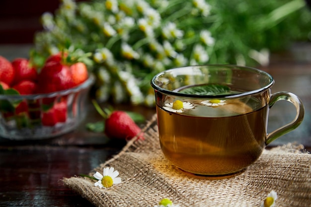 Biologische kamille muntthee kruideninfusie thee antioxidant Verse aardbeien kamille bloemen en munt op houten tafel Natuurlijk zomerontbijt Esthetische zomerse levensstijl Mooi eten