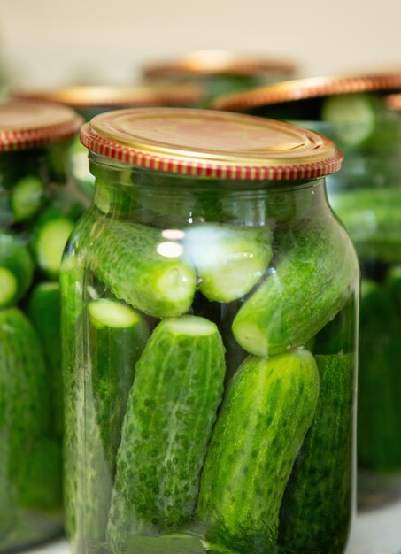 Foto biologische komkommers in potten geplaatst en afgedekt met deksels zijn klaar om te worden ingeblikt