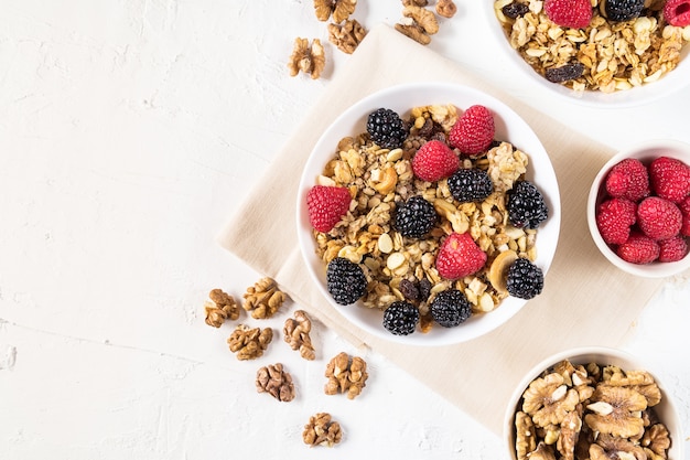 Biologische muesli met verse bessen en cashewnoten op witte achtergrond plat.