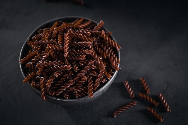 Biologische ongekookte boekweitfusilli pasta op donkere ondergrond. Volkoren glutenvrije noedels. Gezond voedselconcept.