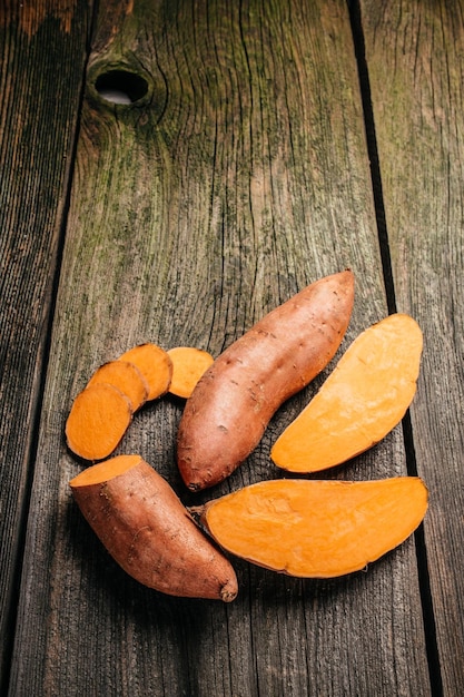 Biologische oranje zoete aardappel. Rauwe zoete aardappelen of batata's. verticaal beeld. bovenaanzicht. plaats voor tekst.