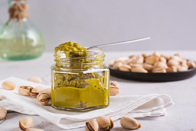 Foto biologische pistache smeerroom in een pot en noten op een bord op tafel