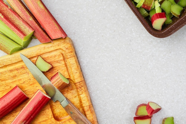 Biologische rabarber op een snijplank koken zelfgemaakte Engelse taart op een keukentafel het proces van het bereiden van een traditionele Britse taart