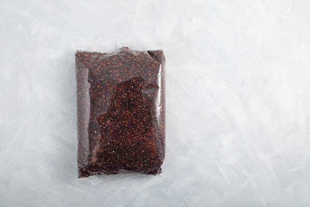 Biologische ragi of zwarte quinoa in een transparante verpakking op lichtgrijze tafel met structuur