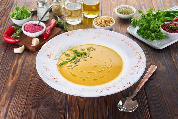 Biologische veganistische pompoencrème soep op houten tafel met ingrediënten, gezonde voeding voedsel concept