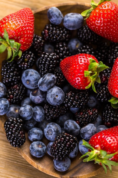 Biologische vers gemengd fruit in houten kom op tafel.