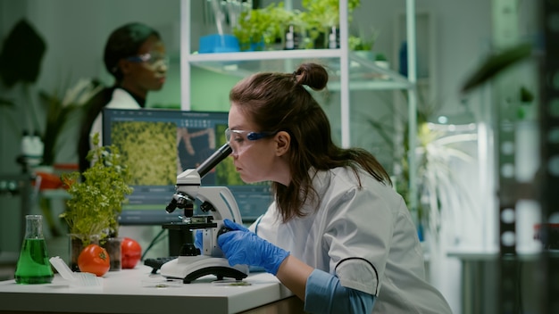 Biologist taking leaf sample putting into microscope