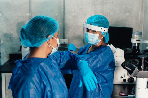 Biologists touching elbows to greet each other during laboratory pandemic