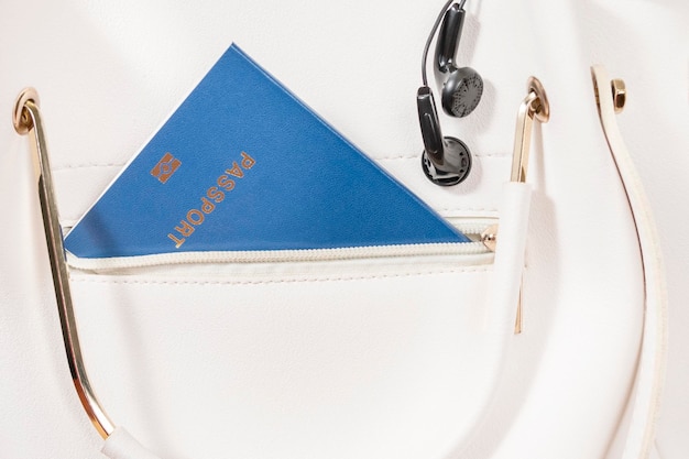 Biometric passport and headphones in a white female handbag, close-up