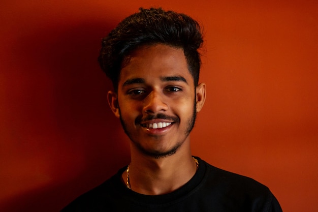 Biometric verification human facial detection high technology\
indian man student holding phone face id scanning orange wall\
background