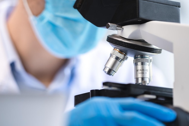 의학 기술 실험의 관점에서 화학 과학 또는 미생물학 분석을 위한 생물학 의학 실험실 장비 연구를 위해 과학 현미경을 사용하는 생명 공학 과학자