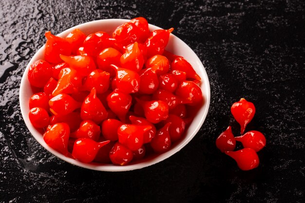 Biquinho Pepper into a bowl. Capsicum Chinense over a wooden table.