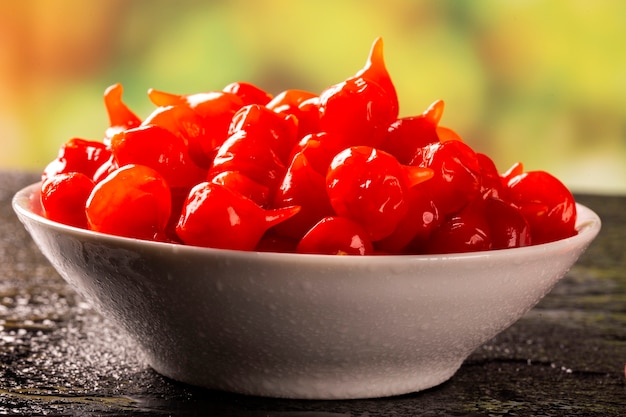 Biquinho Pepper into a bowl. Capsicum Chinense over a wooden table.