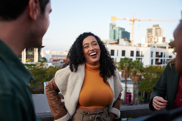 biracial female laughing having a good time with group of multicultural friends socializing on a rooftop terrace at dusk