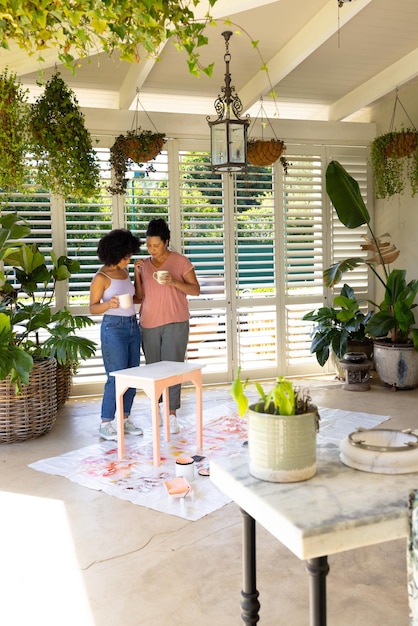 写真 アップサイクリングプロジェクトで家具を一緒に塗る二人種の母親と大人の娘
