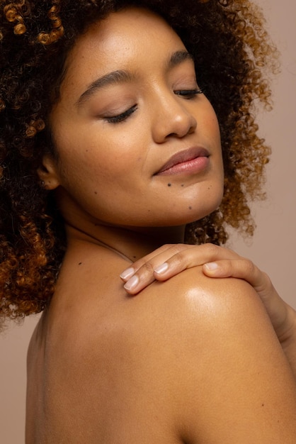 Photo biracial woman with dark curly hair smiling with eyes closed and hand on shoulder